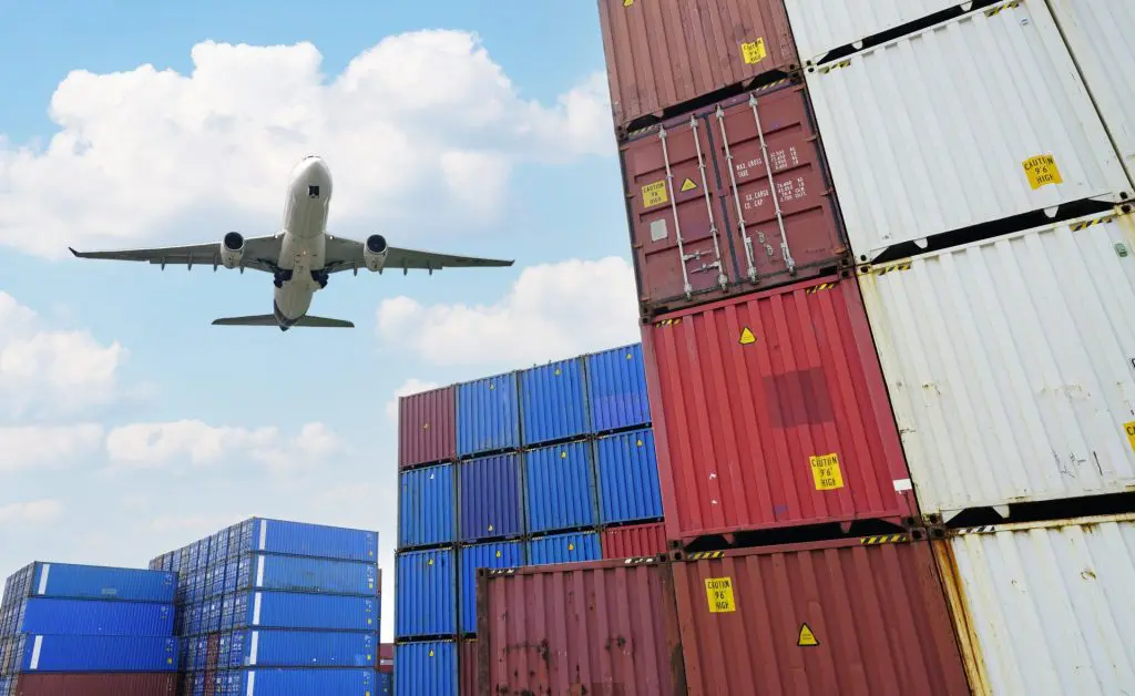 Plane flying over containers 1024x628